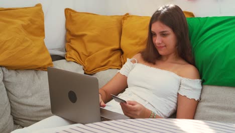 Cheerful-woman-paying-for-order-with-plastic-card-during-online-shopping