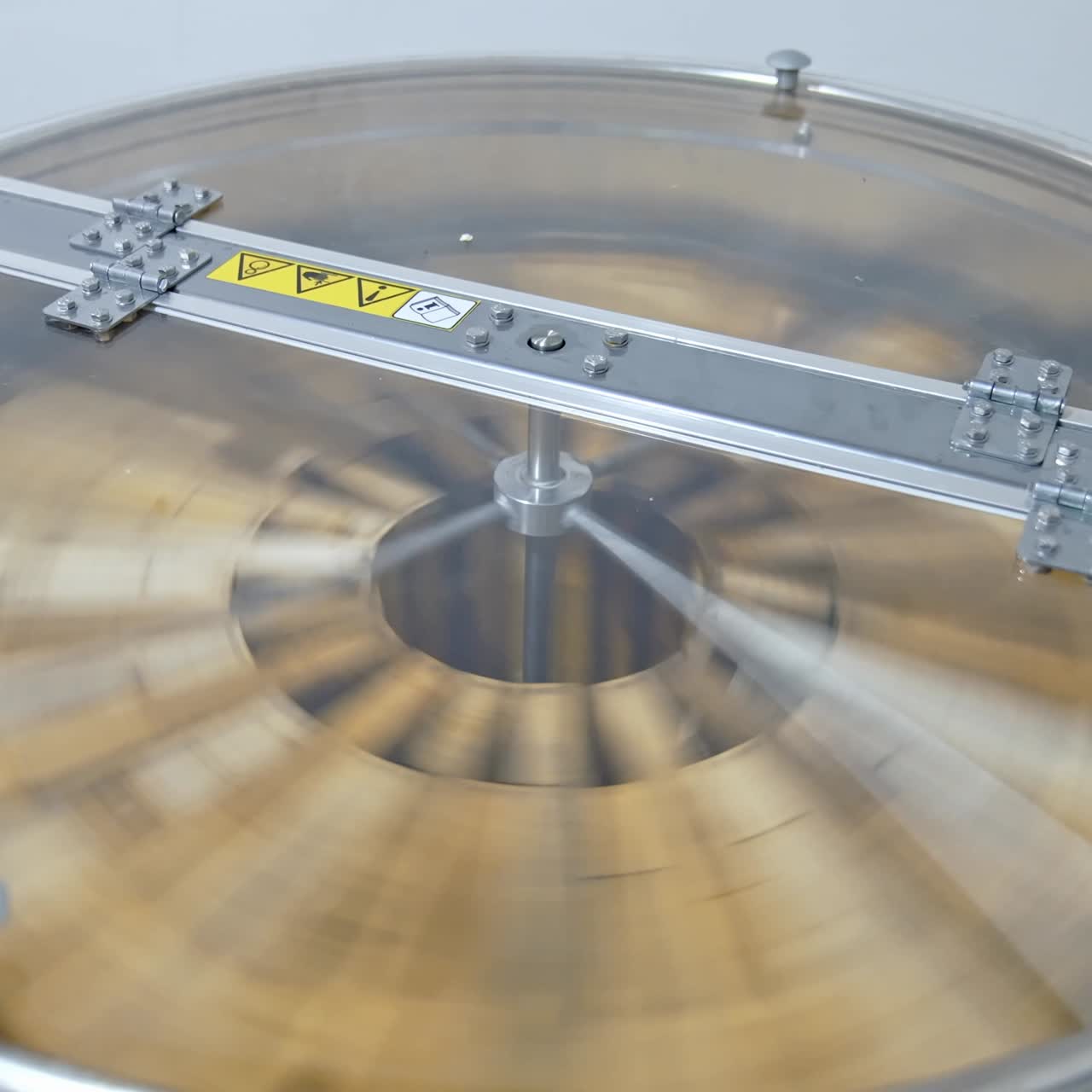 Spinning of frames with honey in a honey extractor. Process of pumping natural honey in modern centrifuge machine. Getting honey from honeycombs in special device. Close-up