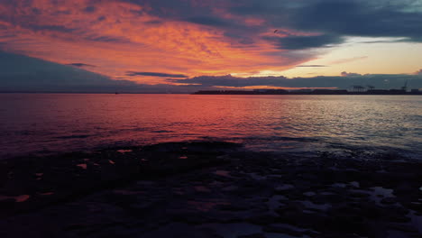 tranquil sunset with red and orange clouds reflecting on surface of ocean, slow