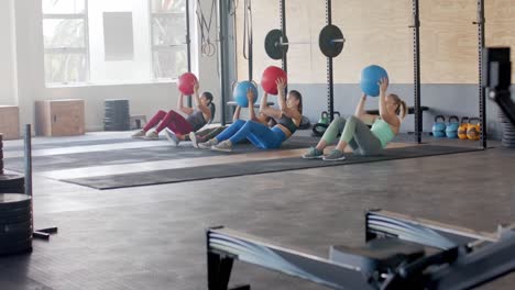 unaltered diverse women group training with medicine balls at gym, slow motion, copy space