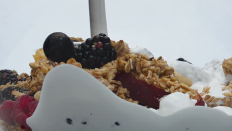 leche vertiendo frutas bayas granola sobre fondo blanco de cerca. comida saludable.
