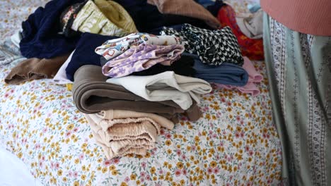 folded clothes on a bed with floral bedding