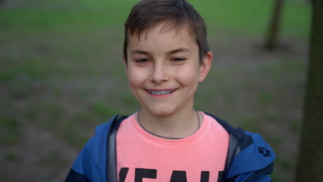 Happy-teen-boy-in-brackets-looking-camera-outdoors.-Handsome-guy-smiling-in-park