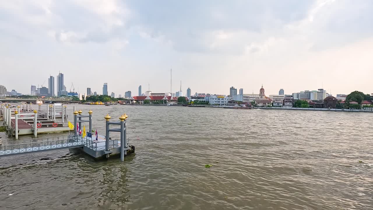 A serene view of the Chao Phraya River with Bangkok's skyline under soft daylight, showcasing urban and natural elements