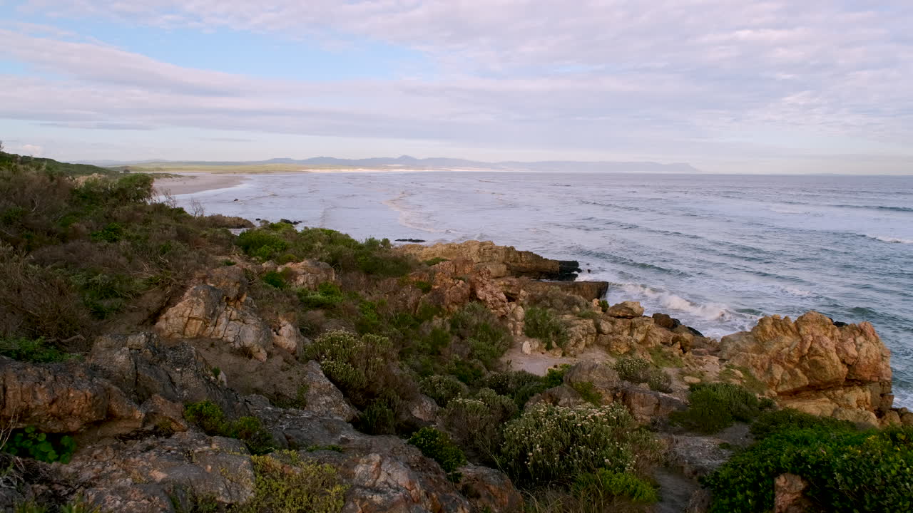 Vegetação costeira e rochas irregulares ao longo da costa de Hermanus, vista de cima