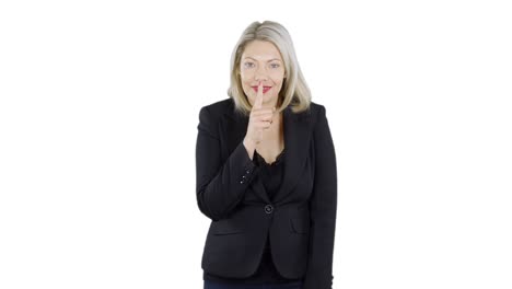 an attractive blonde haired woman is holding her finger to her lips gesturing to be quiet like keeping a secret