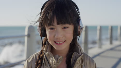 Close-Up-Retrato-Linda-Niña-Asiática-Con-Auriculares-Sonriendo-Disfrutando-Escuchando-Música-En-La-Playa-Junto-Al-Mar