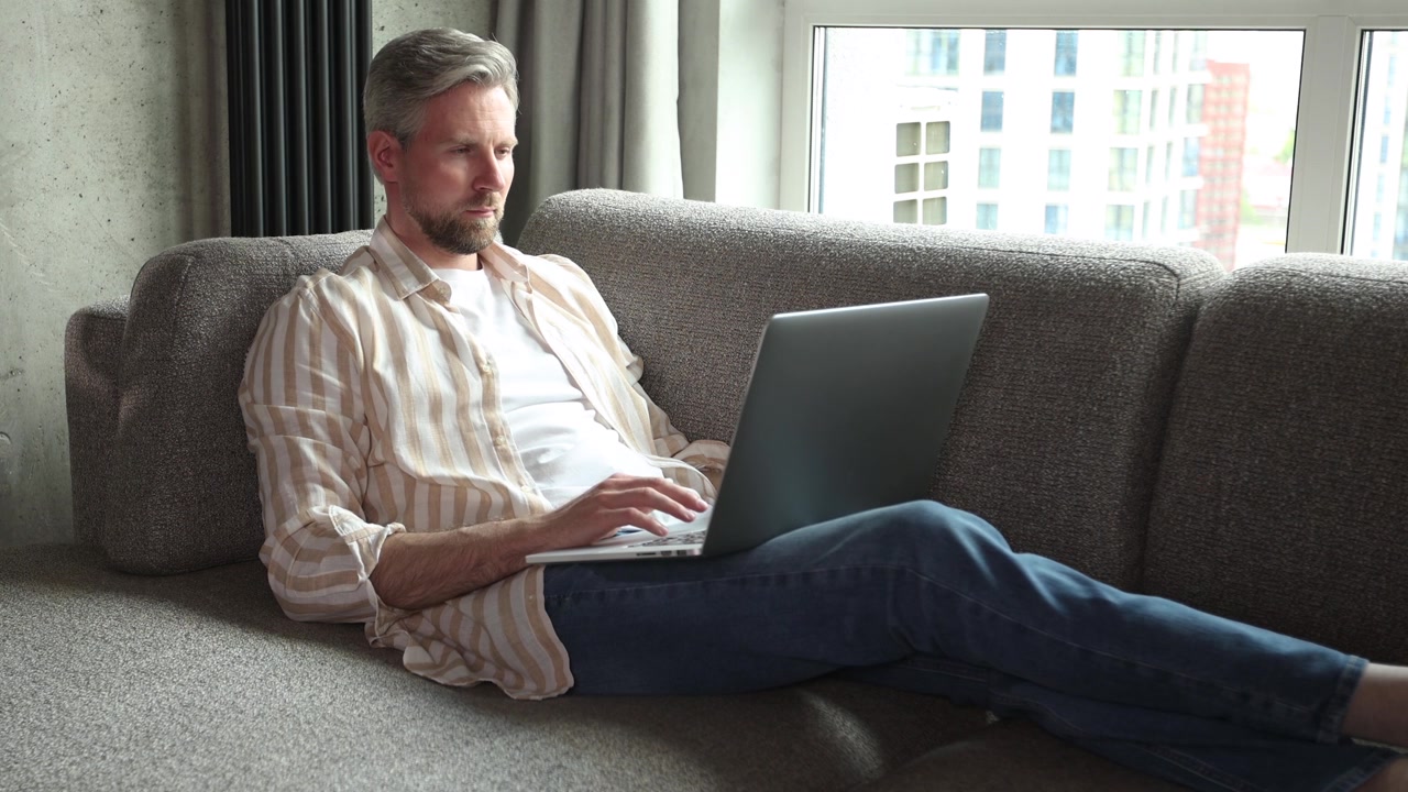 Relaxed Man Working on Laptop from Home Sofa