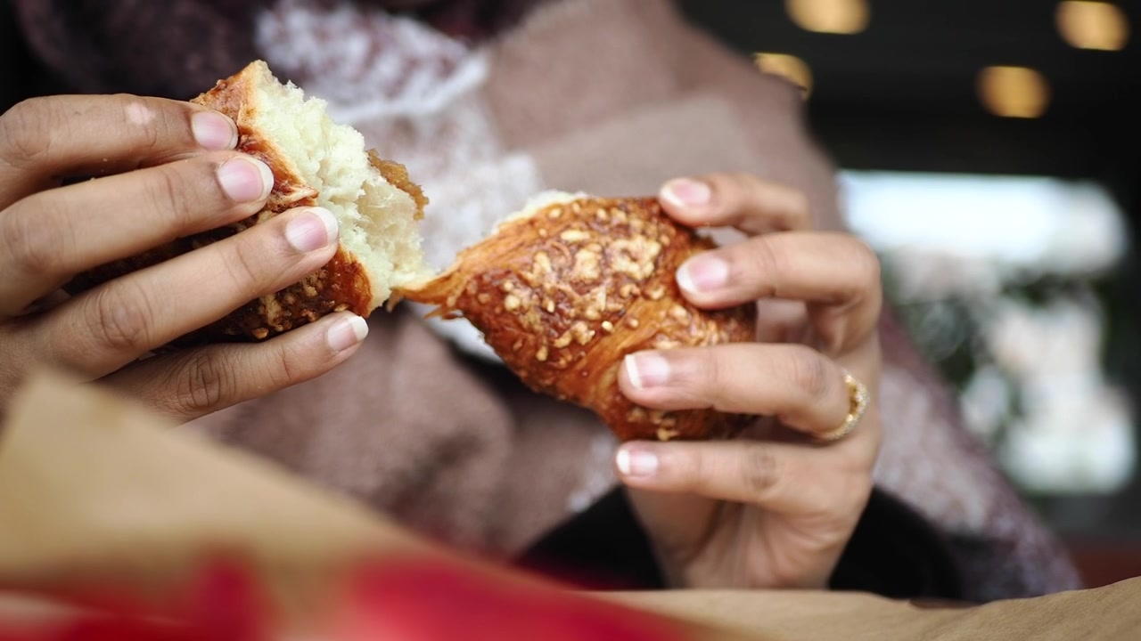 Person Breaking a Fresh Croissant in Half