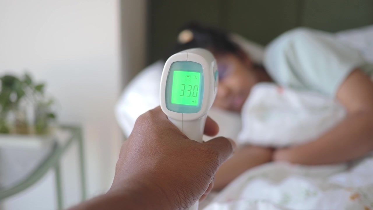 Persona che controlla la temperatura di una donna che dorme con un termometro a infrarossi.