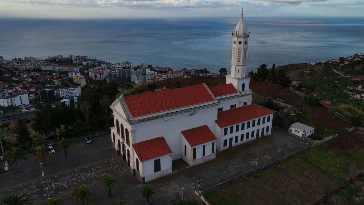 iglesia de são martinho en funchal, madeira: vista aérea de la hermosa iglesia y su torre blanca durante la puesta de sol, con vistas a la ciudad y el océano