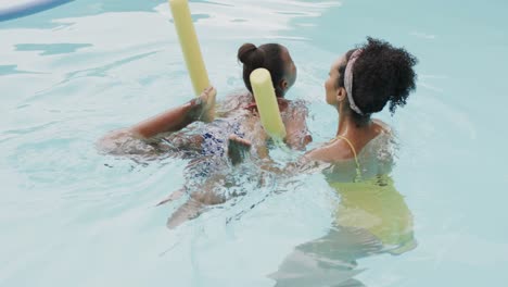 Happy-african-american-mother-and-daughter-playing-in-swimming-pool-in-garden,-slow-motion