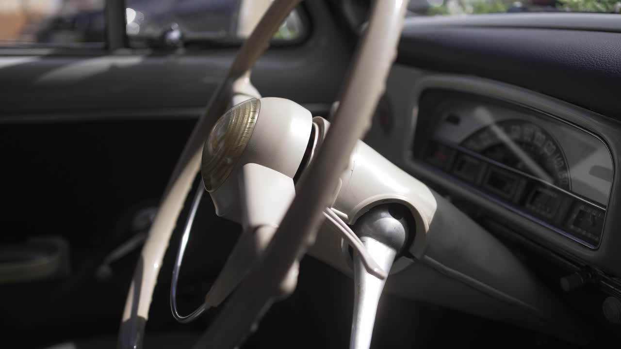 Close up of vintage car steering wheel and dashboard with sunlight streaming through