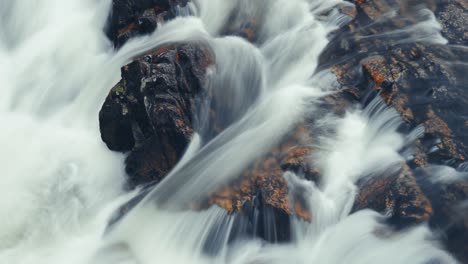 a powerful torrent of whitewater rushes over the dark rock in the long exposure video