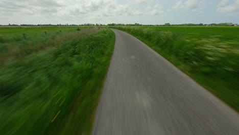 Drone-following-a-country-road-between-grass-fields-in-a-rural-area-in-Zeeland