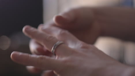 close up of a man's left hand as he fidgets with his wedding ring, ultimately taking it off