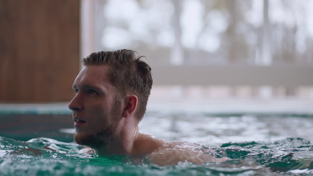 성인 남자가 수영장에서 혼자 수영하고 주말에 온천 목욕과 웰빙 센터에서 휴식을 취하고 있습니다.