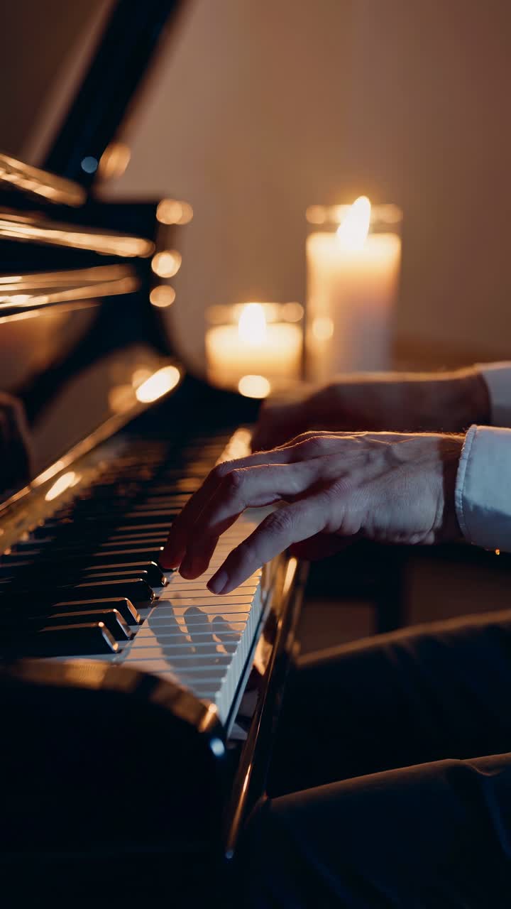 Close-up video of hands playing piano, with soft candlelight creating a warm, intimate atmosphere
