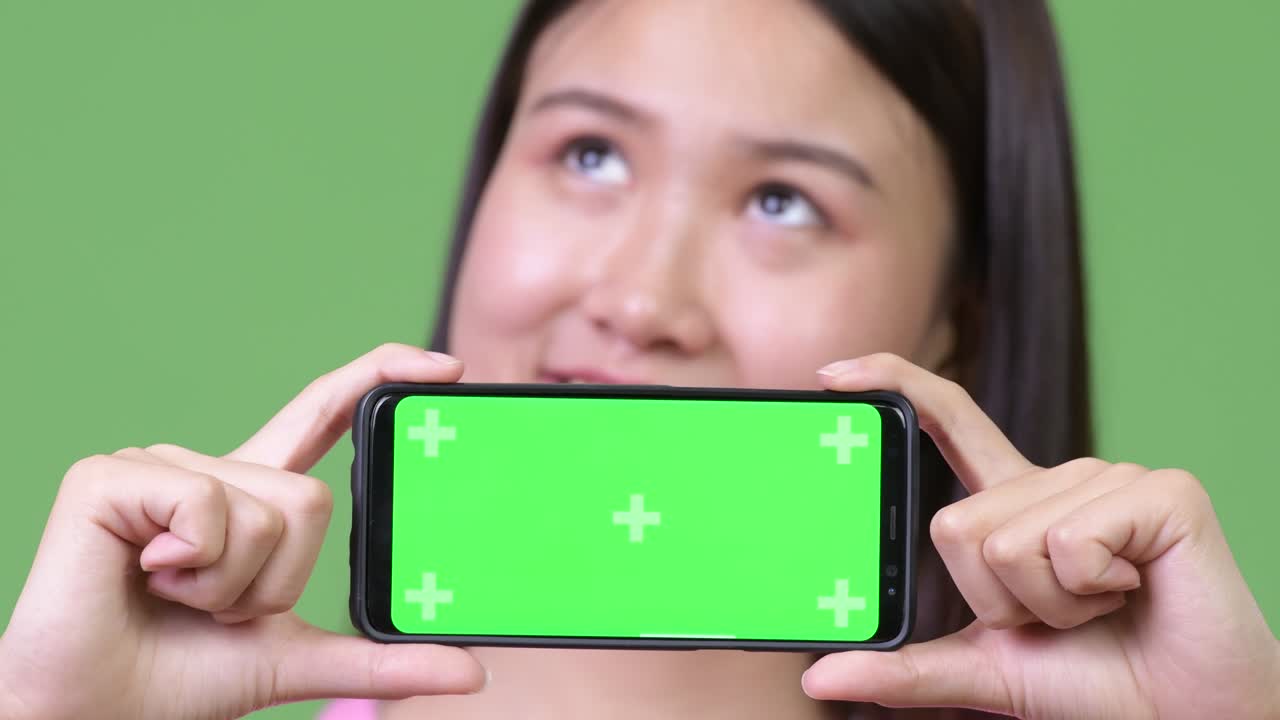 Young beautiful Asian woman showing phone