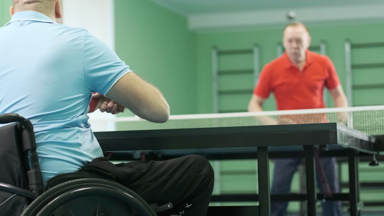 체어에 앉아 있는 남자가 핑핑을 하고, 장애인들이 탁구를 하고, 장애인의 재활, 패럴림픽 스포츠.