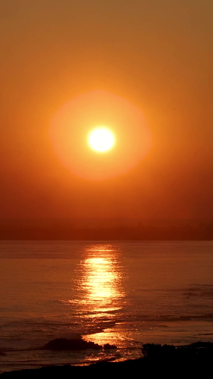 En rolig solopgang over havet med gyldne refleksioner på vandet, der skaber en fredelig og varm atmosfære