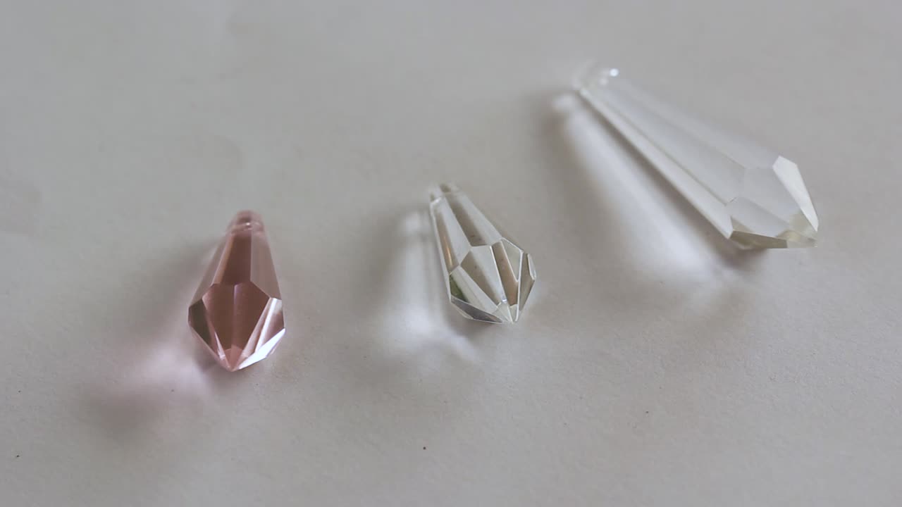 крупным планом длинные кусочки стеклянного кристалла на белом фоне - преломление света прозрачного кристалла