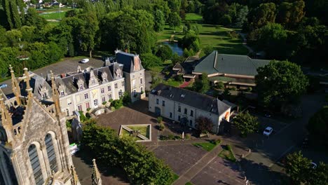 Drone shot descending towards Saint-Pierre Church in Changé, with the Parc des Ondines visible in the background