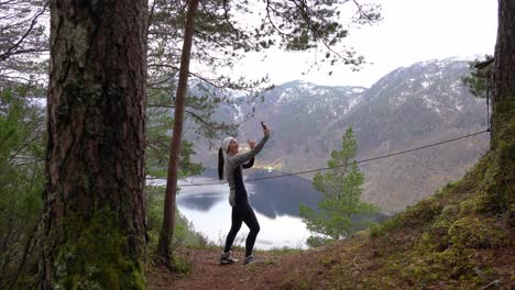 woman on hike stops at overlook above lake to takes selfie with cell phone