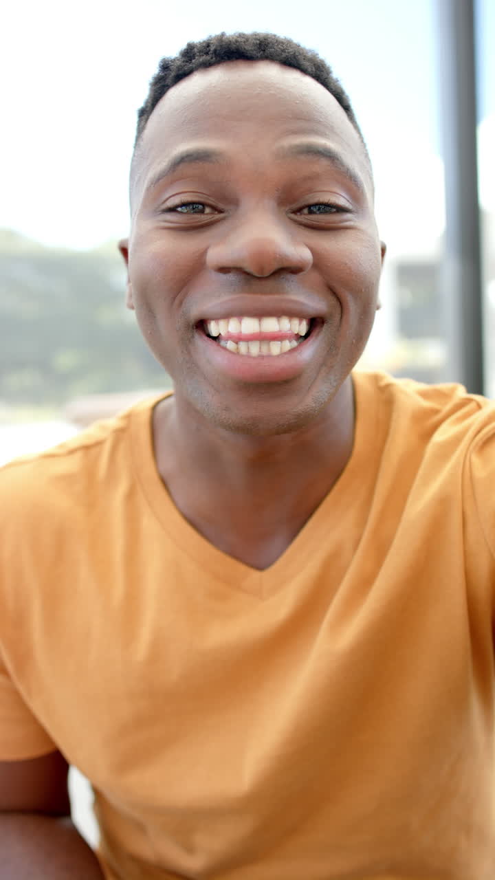 Vertical video of portrait of happy african american man having video call in slow motion