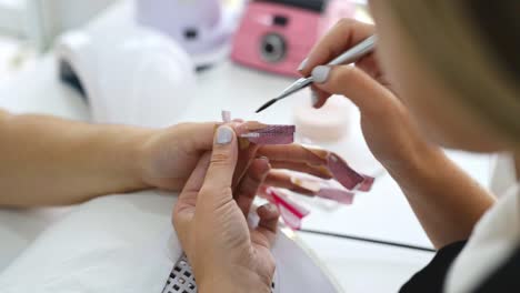 maestra de cultivos aplicando laca en las uñas del cliente en el salón