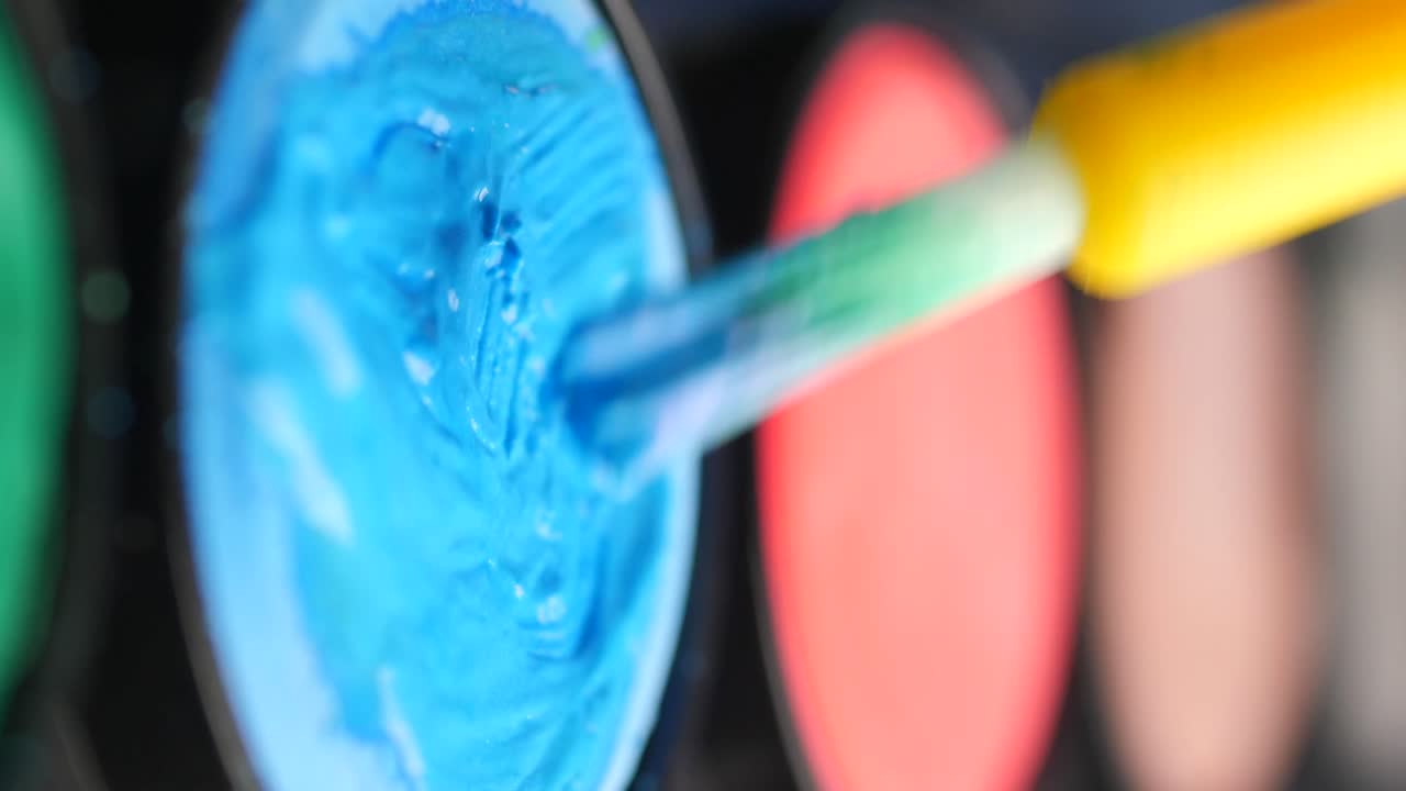 Close-up of a paint brush mixing colors in a palette