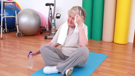 Tired-senior-woman-on-exercise-mat-