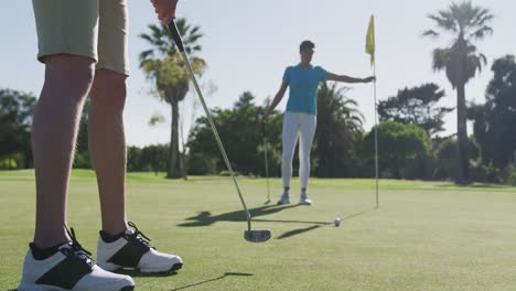 Two-caucasian-women-playing-golf-one-taking-shot-from-bunker