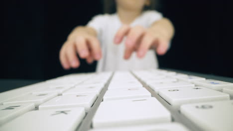 Un-Niño-Con-Camiseta-Juega-Con-El-Teclado-En-La-Mesa-En-Un-Espacio-Oscuro