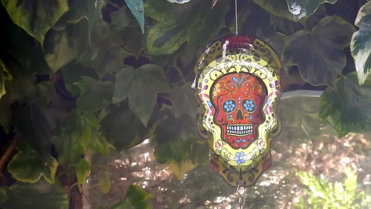 cráneo de azúcar de metal hipnótico decorativo colorido ornamento de jardín giratorio colgando del primer plano del árbol