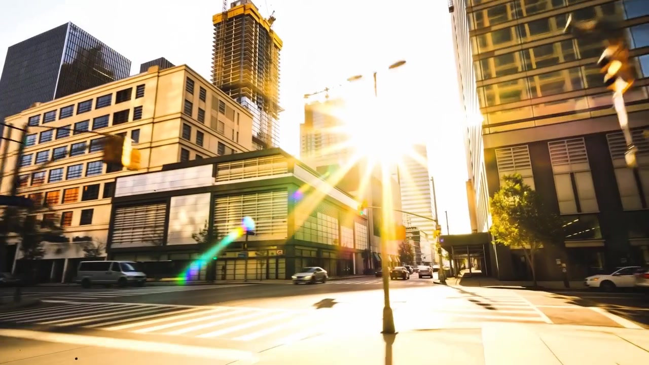 Rastreando um brilho solar central, câmera avançando em direção ao sol na calçada, com reflexo da lente ofuscando.