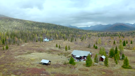 helicopter landing near a cabin in a mountainous forest