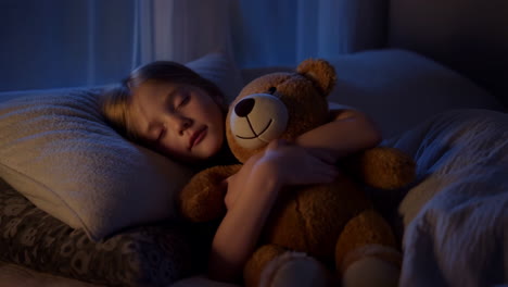a child sleeping with a teddy bear