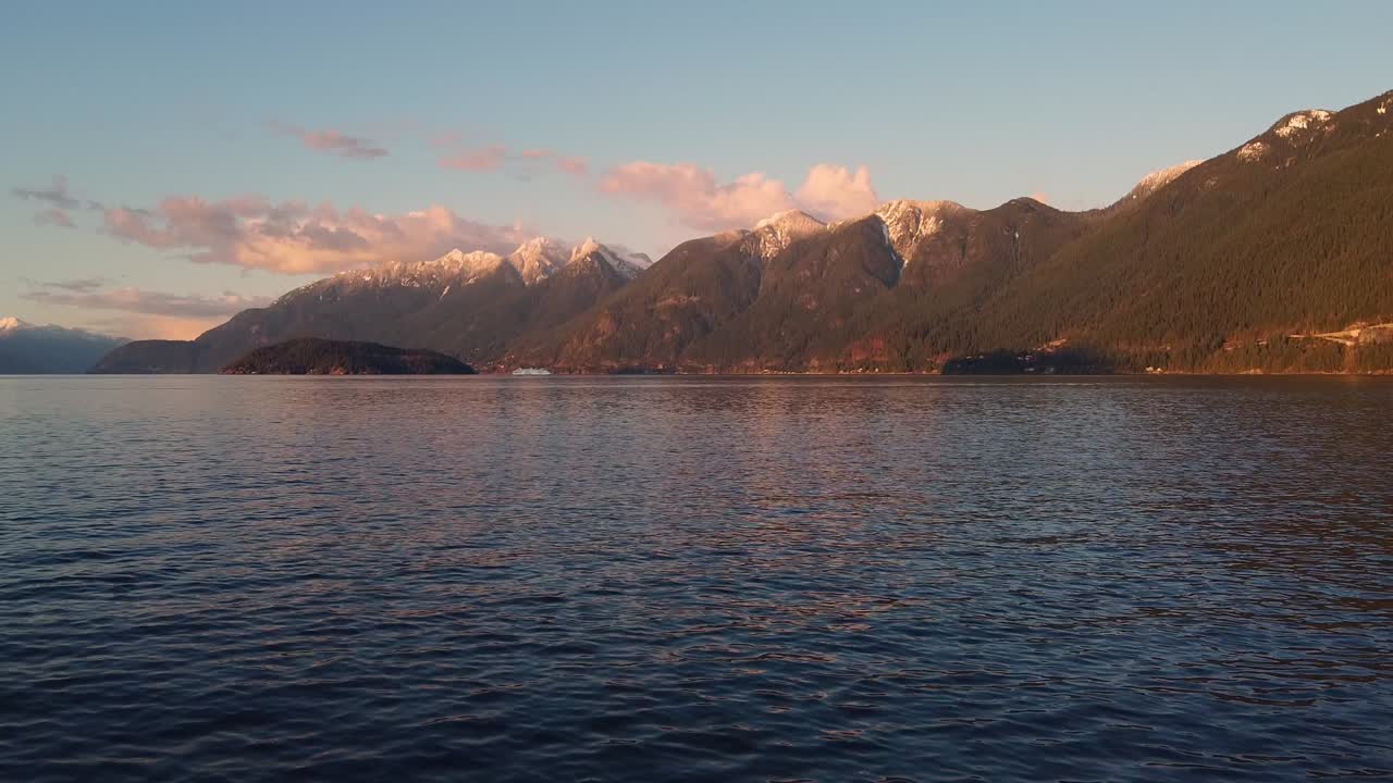 Aerial of BC snow-capped mountainous landscape tilt up from ocean (Sunset)