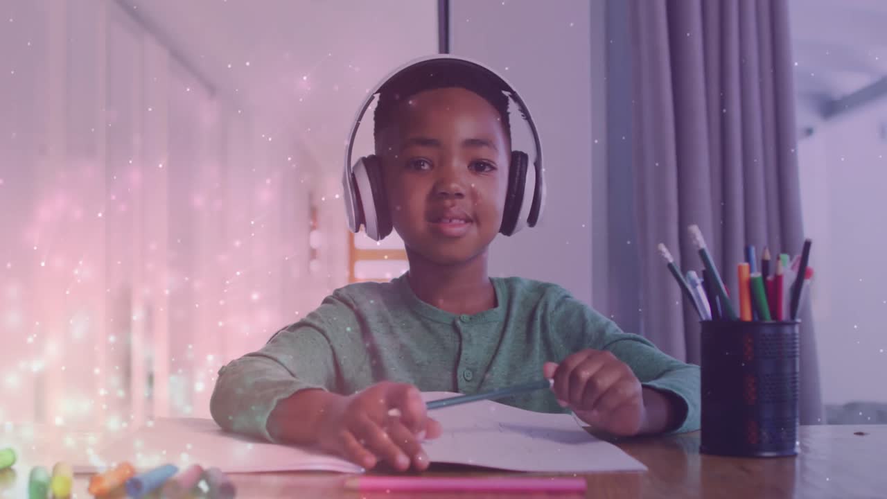 Animation of lights over happy african american boy wearing headphones and doing homework