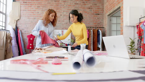 Happy-diverse-female-fashion-designers-discussing-fabrics-in-studio,-slow-motion