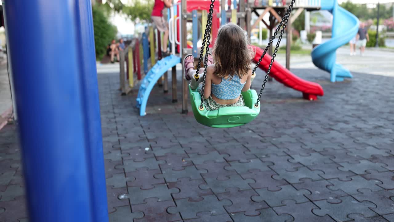 niño en un columpio en un patio de recreo