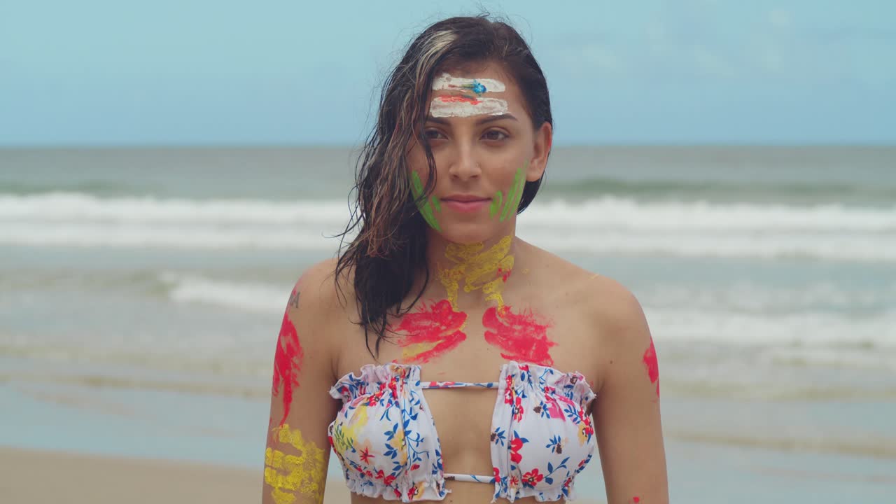 Na karaibskiej plaży dziewczyna w bikini i z malunkami na ciele wygrzewa się na słońcu w słoneczny dzień.