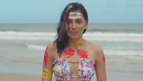 On-a-Caribbean-beach,-a-girl-dons-a-bikini-and-body-paint,-soaking-up-the-sun-on-a-bright-day