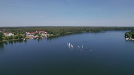 Sailboats-sail-on-a-lake,-distan-drone-parallax-shot