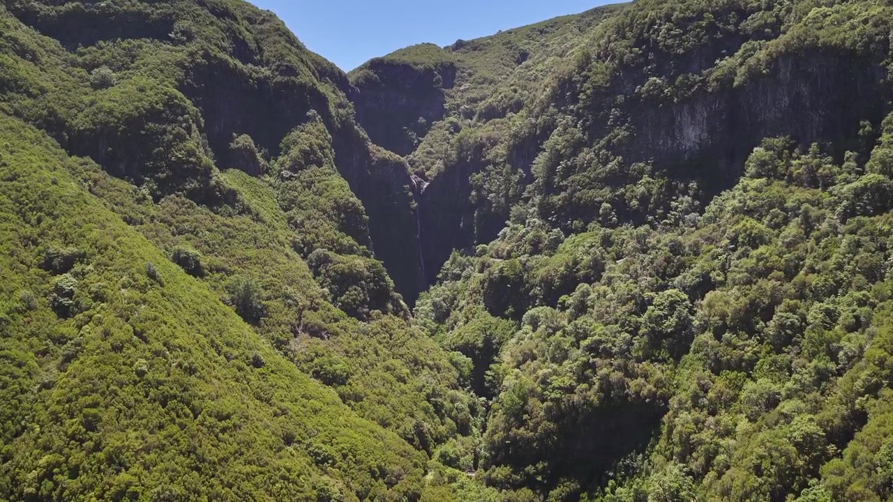 Veduta Aerea della Cascata del Risco che si Getta nella Verdeggiante Levada das 25 Fontes, Circondata da una Fitta Foresta di Alloro e Montagne Aspre sotto la Luce del Giorno, Ripresa da Drone
