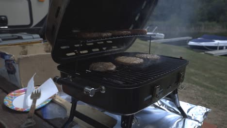 Hombre-Poniendo-Salchichas-Junto-Con-Las-Empanadas-De-Carne-Y-Cerrando-La-Parrilla