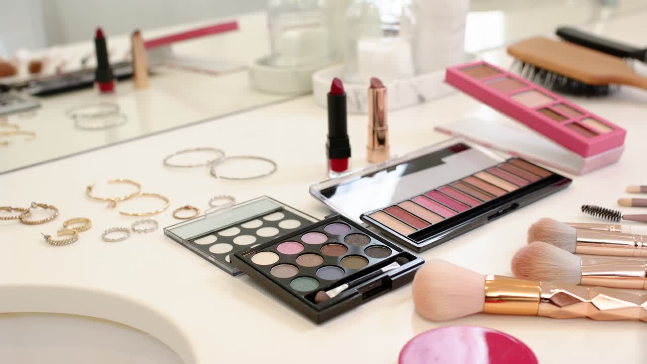 Camera is panning right, revealing palettes, red lipstick and brushes on vanity, showing detail