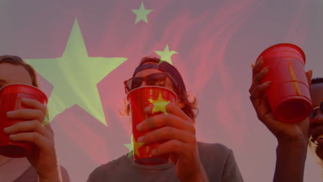 holding red cups with chinese flag overlay, people participating in outdoor animation