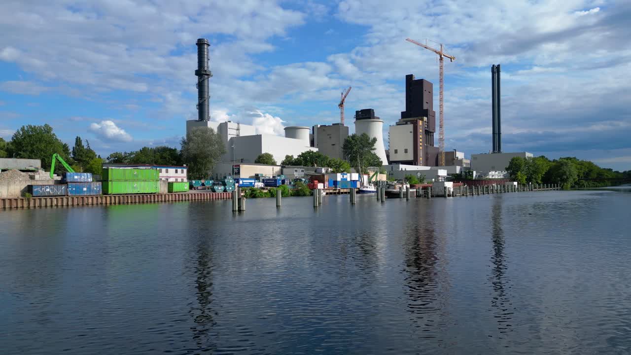 Power plant undergoing conversion, retrofitting and renewal, featuring cooling towers, chimneys, and construction crane. Smooth aerial view flight pull in drone